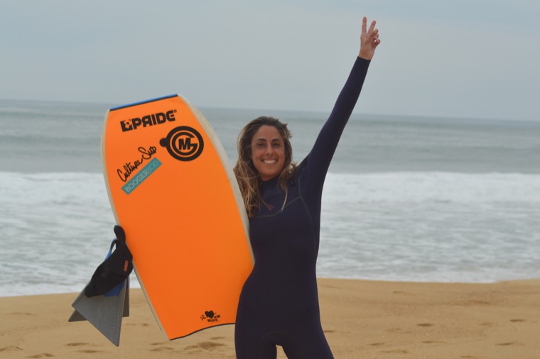 Anne-Cécile avec une planche de bodyboard orange.