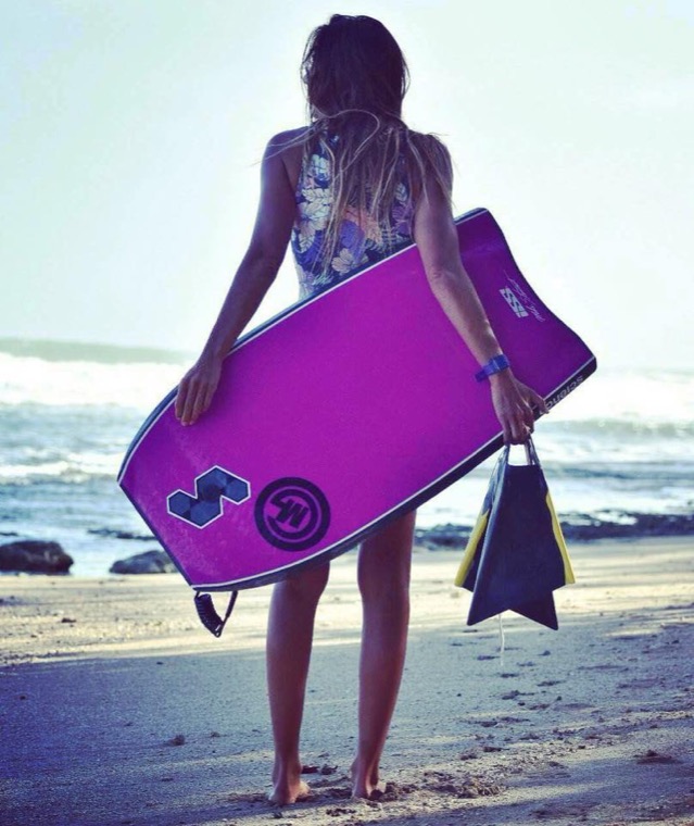 Anne-Cécile de dos avec sa planche rose.